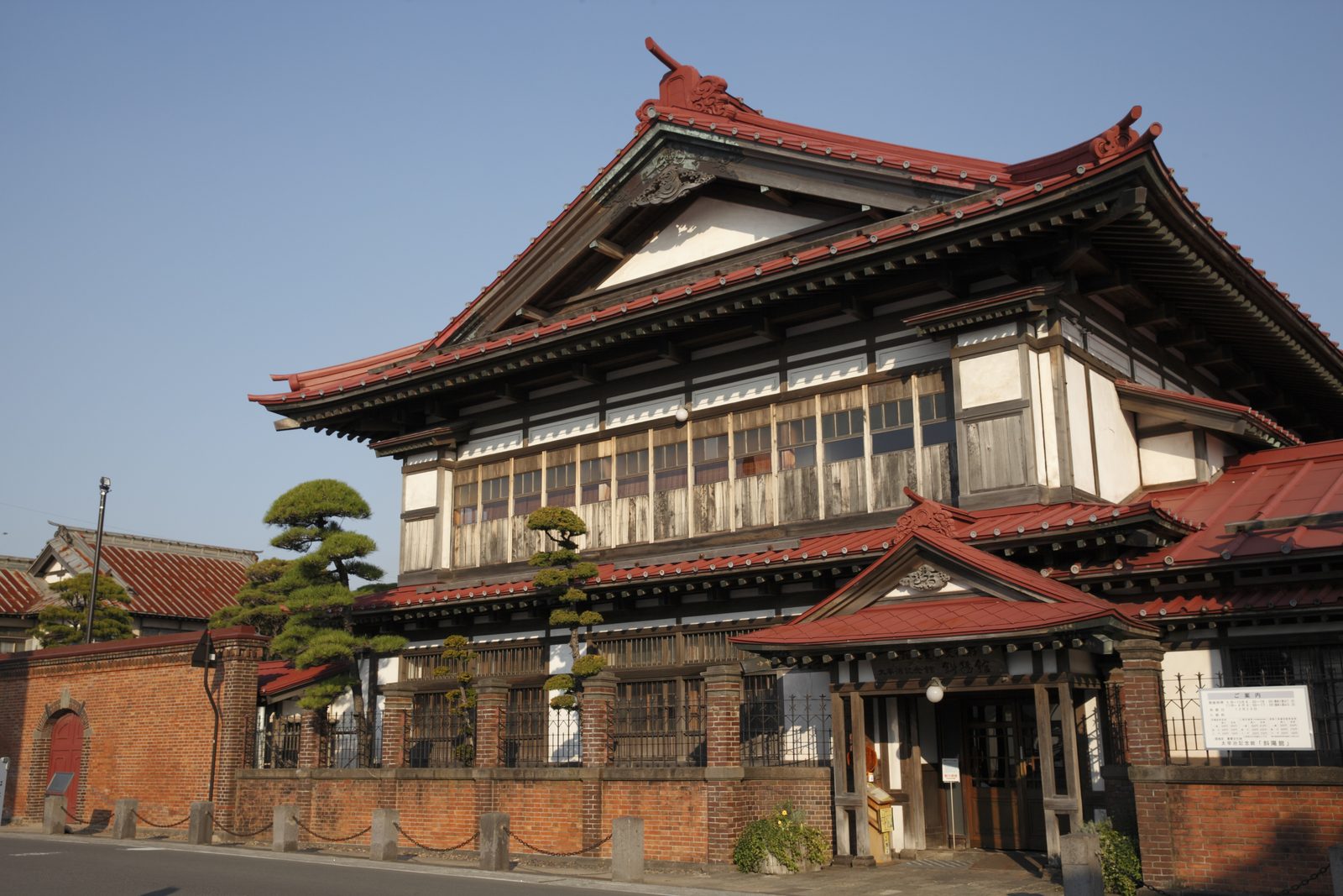 The red-roofed, two-storey Shayokan, the former Tsushima family mansion in Kanagi, behind its brick wall
