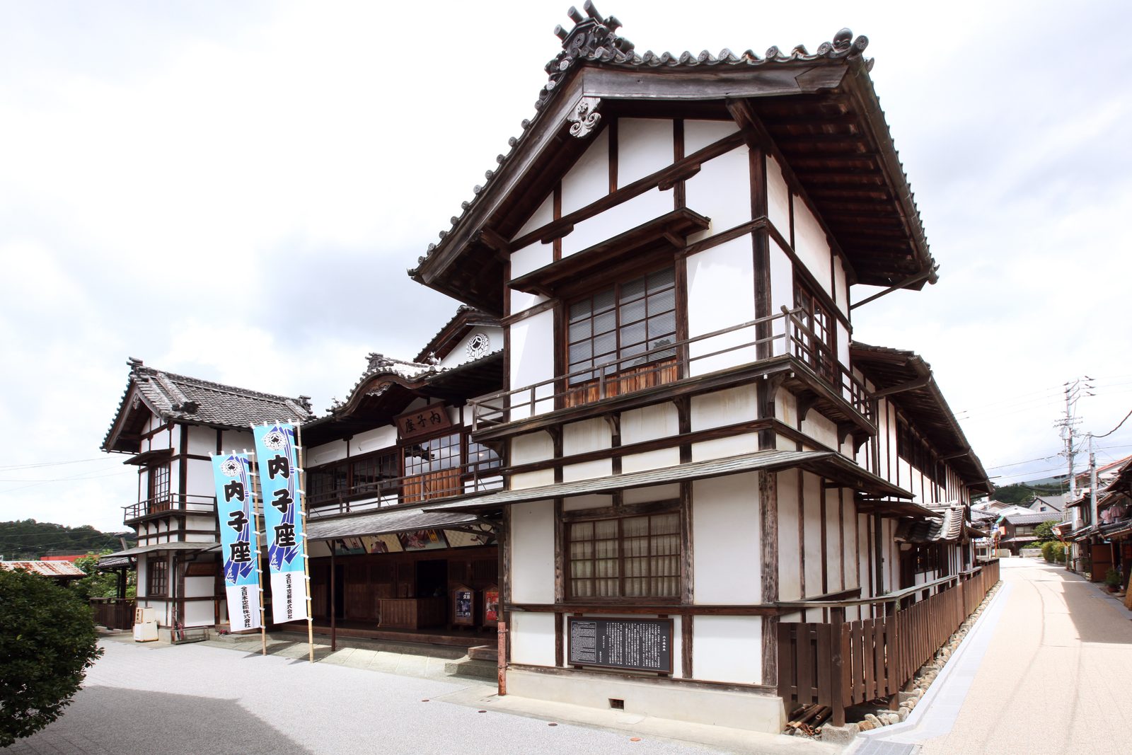 The Uchiko-za theatre, a two-storey wooden building with white plaster walls, dark timber framing and tiled roofs, with banners reading Uchikoza at the entrance
