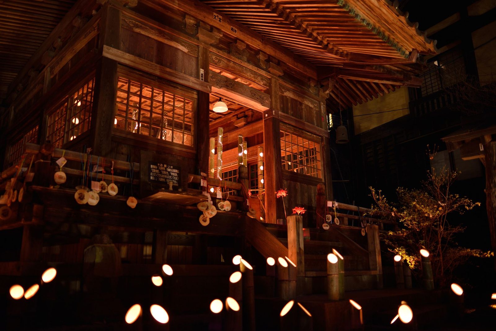 The wooden Jizo hall in Kurokawa Onsen lit up at night, with small lanterns glowing in front