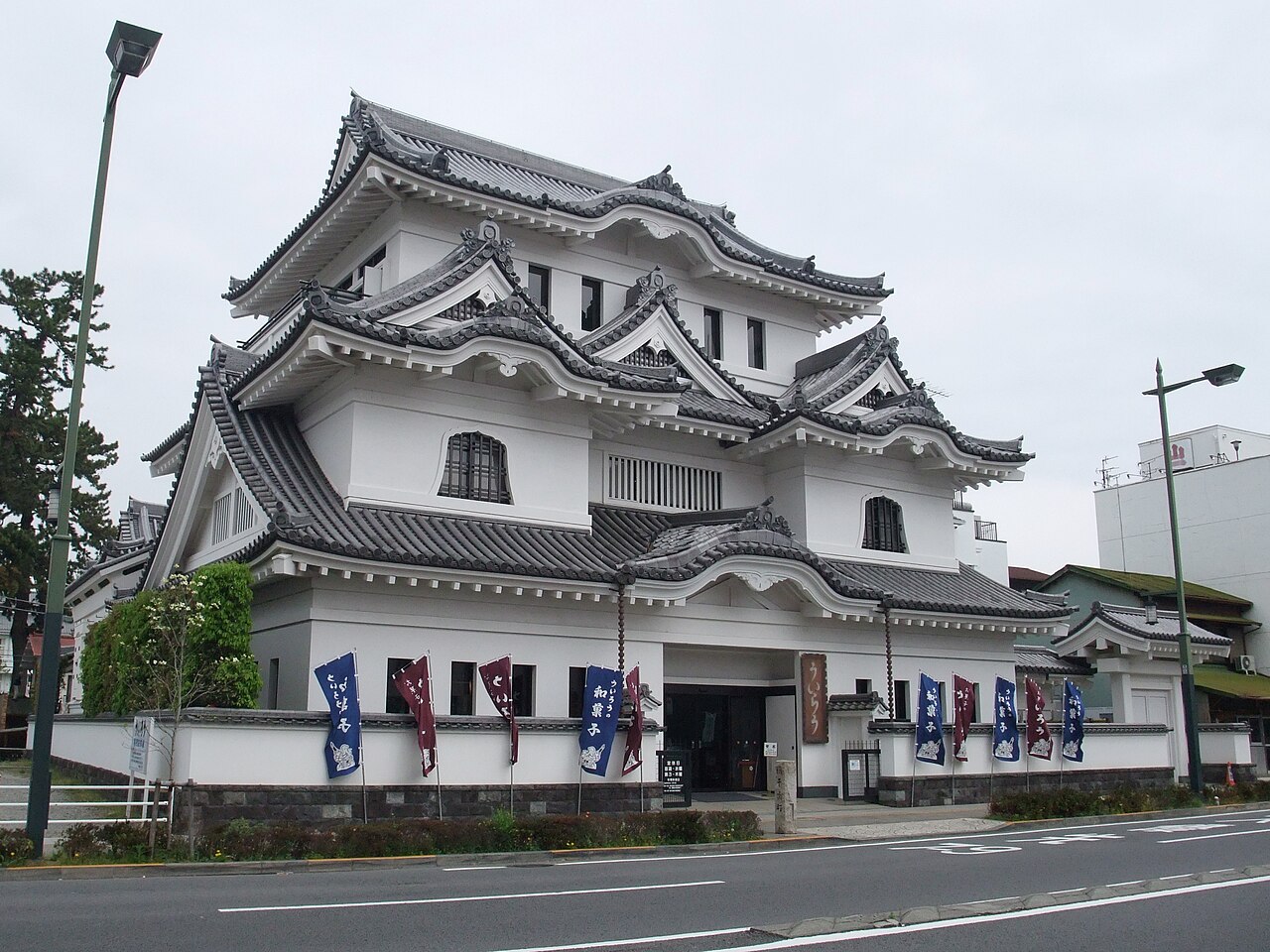 The white castle-style main shop of Uiro in Odawara, with blue and dark-red banners, seen across the road.