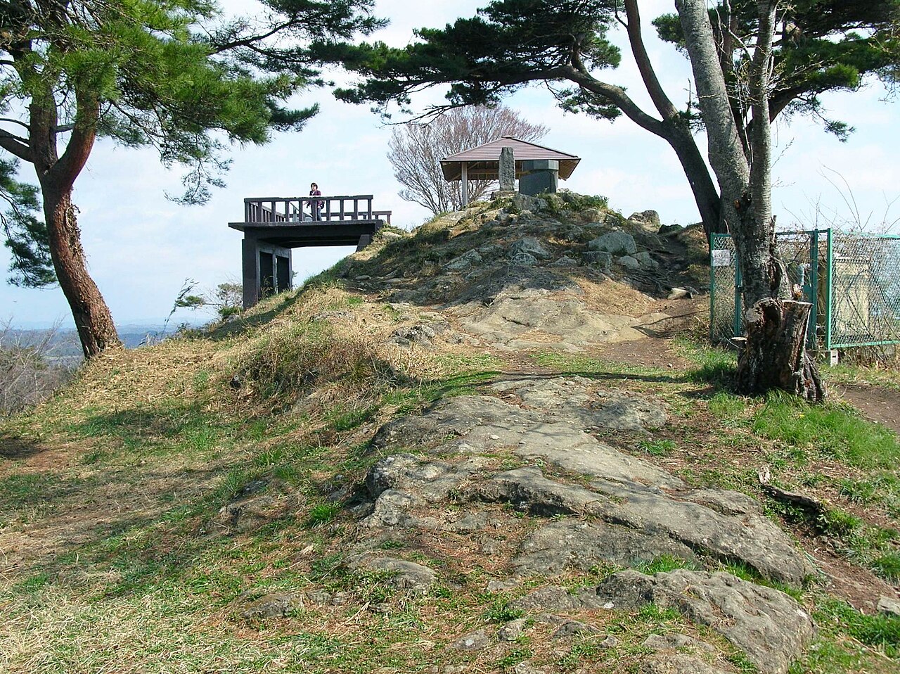 A timber viewing deck and a small roofed shelter on the rocky summit of Otakamori, framed by wind-bent pines.