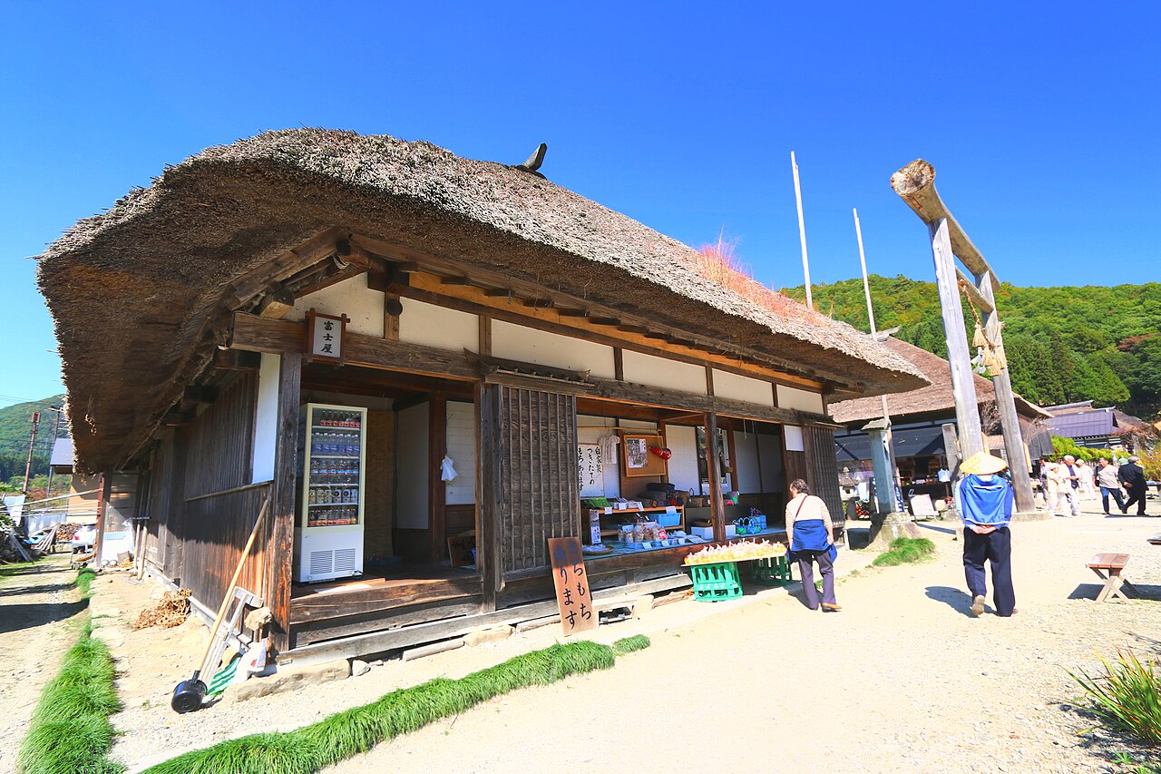 A thatched-roof shop with a wooden torii beside the road in Ouchi-juku.