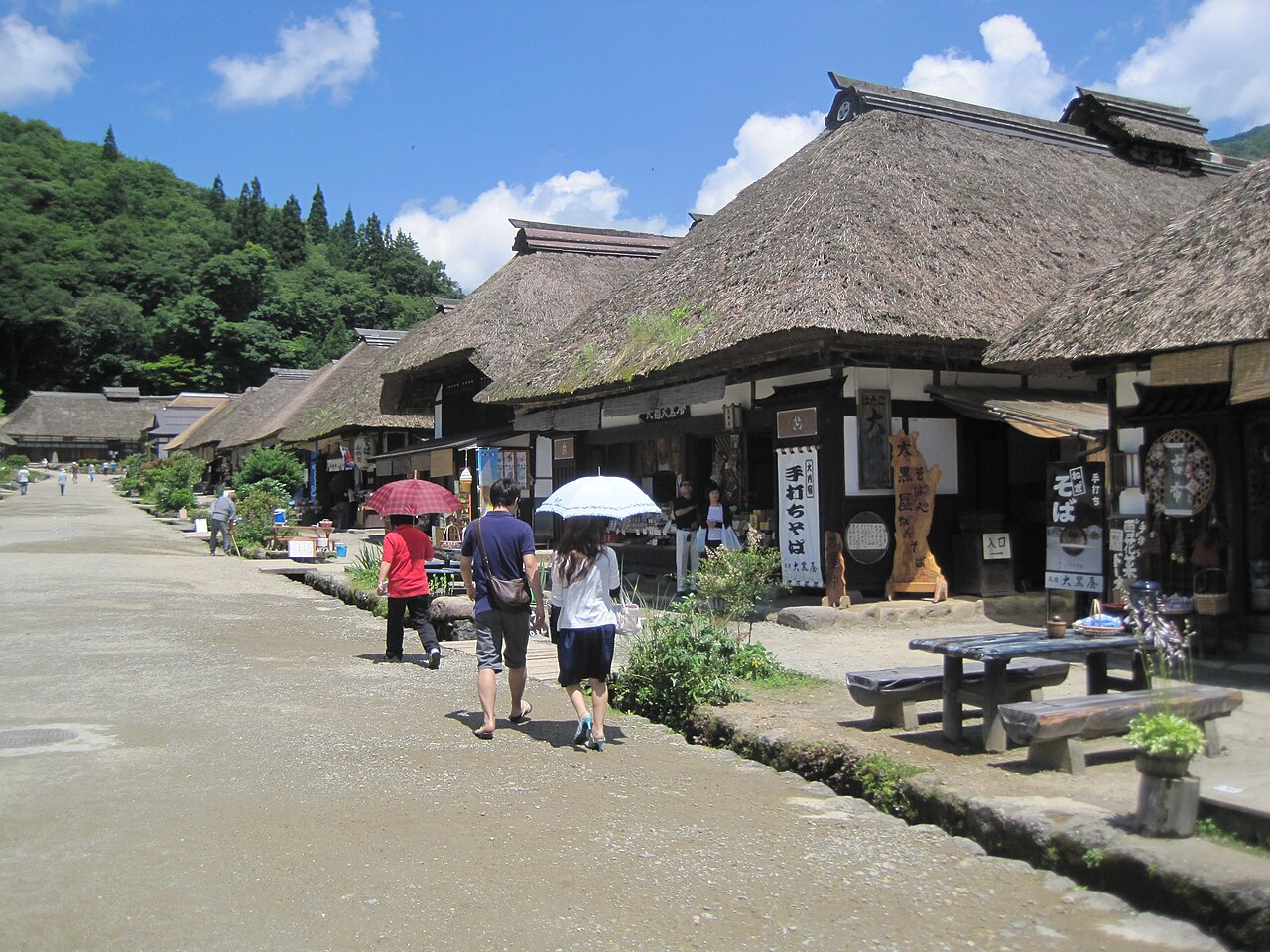 Thatched-roof shops line the main street of Ouchi-juku under a summer sky.