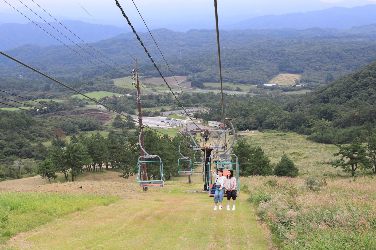 Chairlift climbing a grassy slope on Mount Sanbe with the valley below