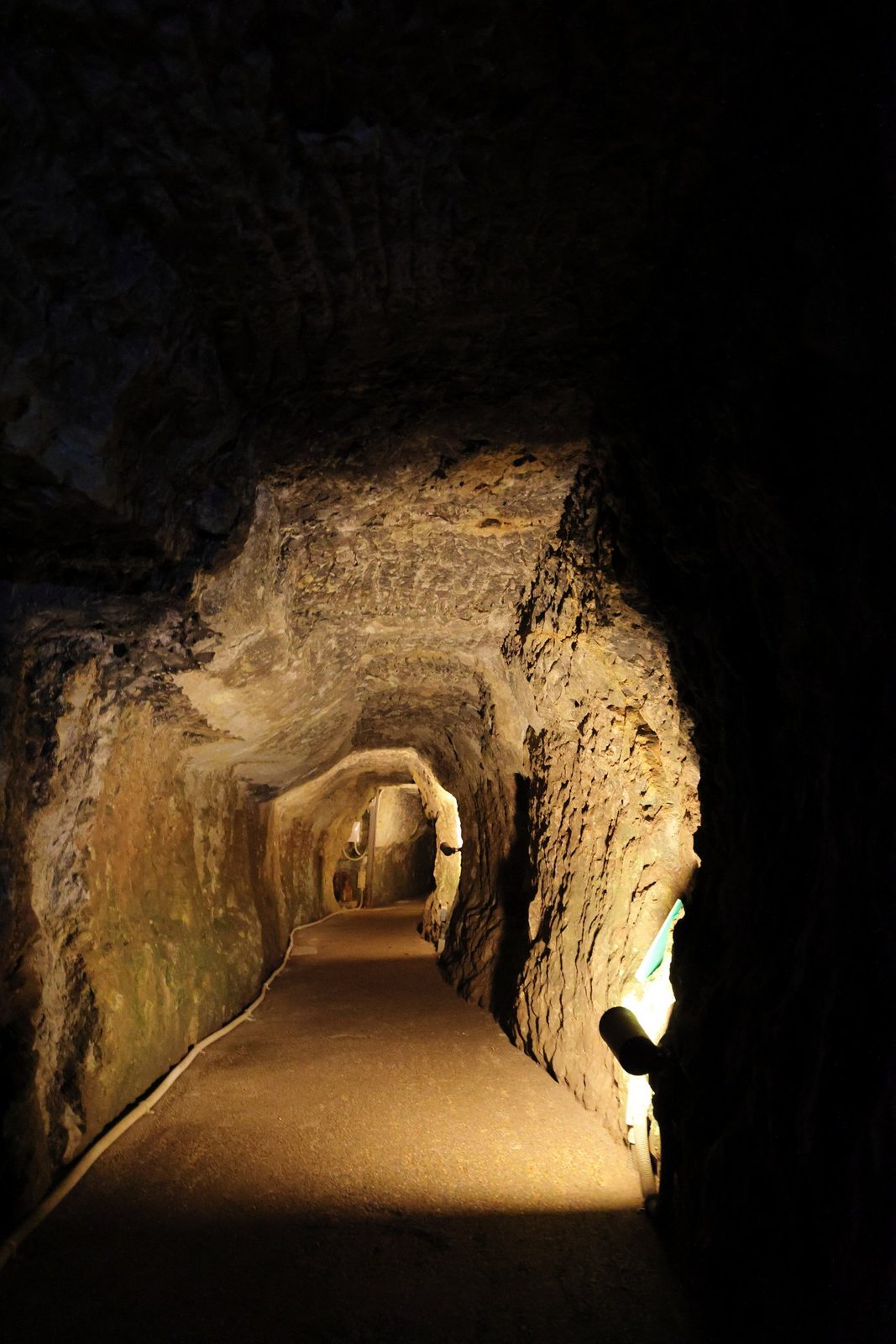 Inside the Ryugenji Mabu tunnel, a rough-hewn rock passage lit softly along a walkway