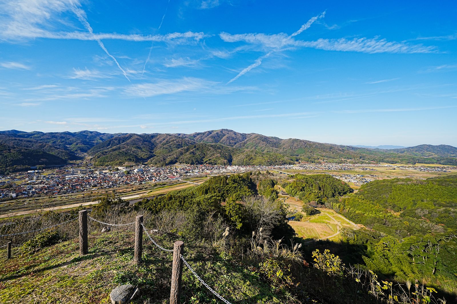 View from a hilltop over a town, a river and the surrounding green mountains