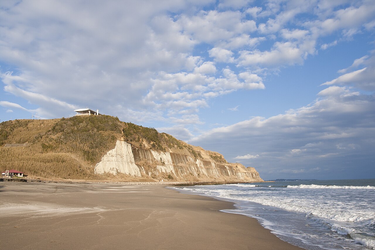 A wide sandy beach and breaking surf below the tall bluffs of Byobugaura on the Choshi coast