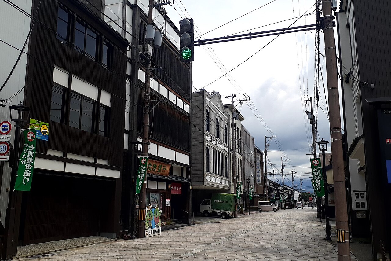 A quiet street in Ono lined with dark traditional wooden shopfronts and old townhouses, with utility poles and an overcast sky.