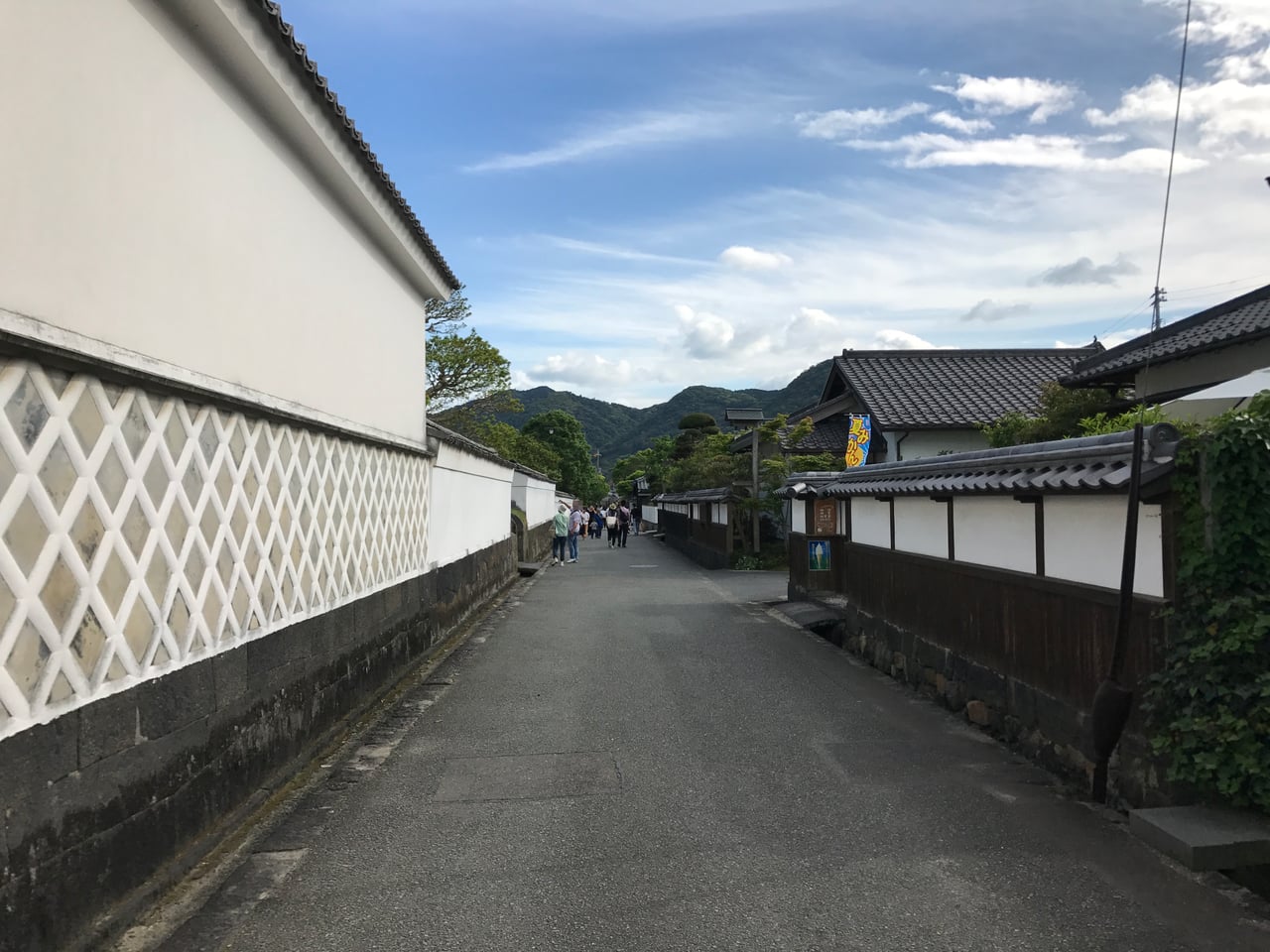 A narrow lane between whitewashed plaster walls and clipped hedges in the Kikuya Yokocho lane of Hagi's old castle town.