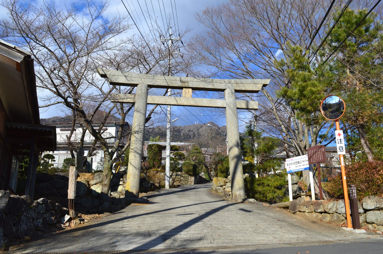 A large stone torii gate marking the approach road to Tsukubasan Shrine, with Mount Tsukuba rising behind.