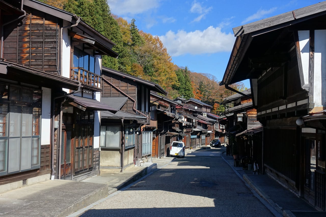 Wooden inns and shops line the old Nakasendo post-town street of Narai-juku, Nagano, in autumn color.