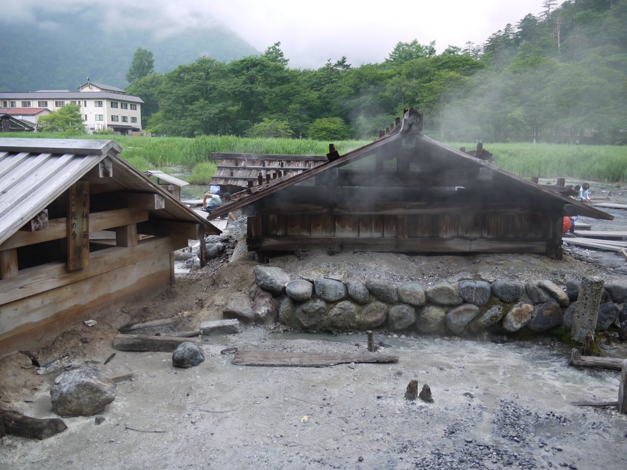 Steam rising from the hot-spring source at Nikkō Yumoto Onsen, with the buildings of the small hot-spring town beyond.