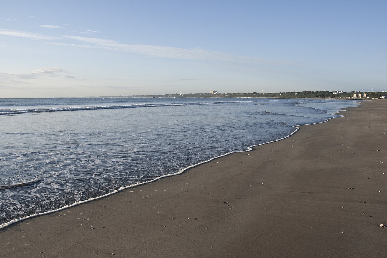 A quiet sandy beach with a gently breaking wave under a pale morning sky on the Oarai coast