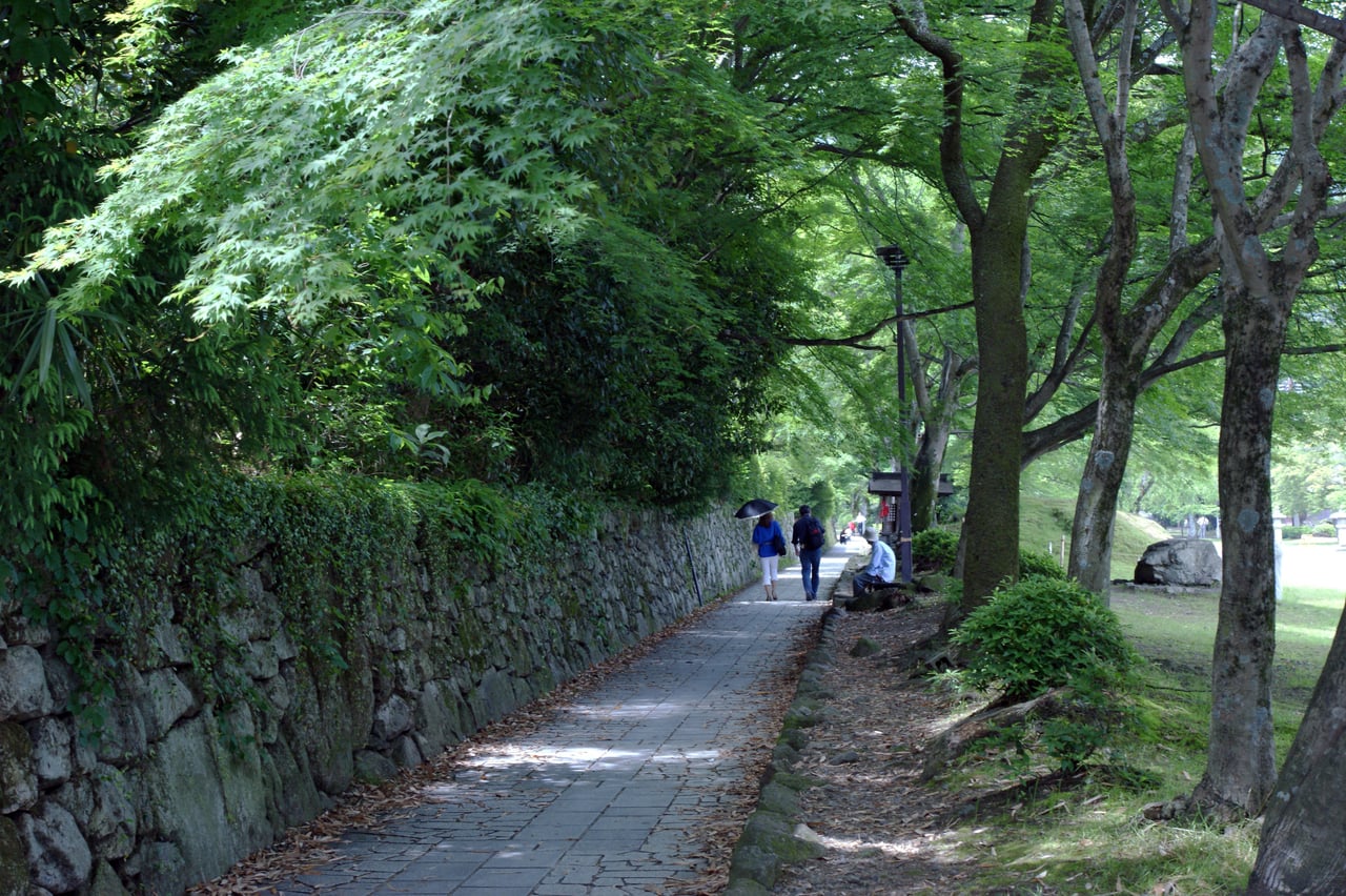 A stone-walled pathway shaded by trees in Sakamoto, the temple-town foot of Mount Hiei, near the sub-temples of Enryaku-ji.