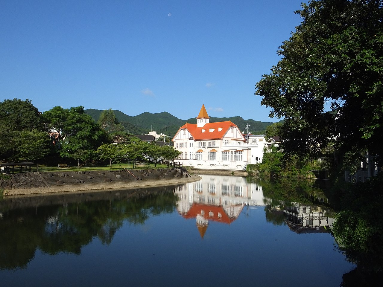 Siebold no Yu reflected in the Shiota River in Ureshino Onsen, with green hills behind