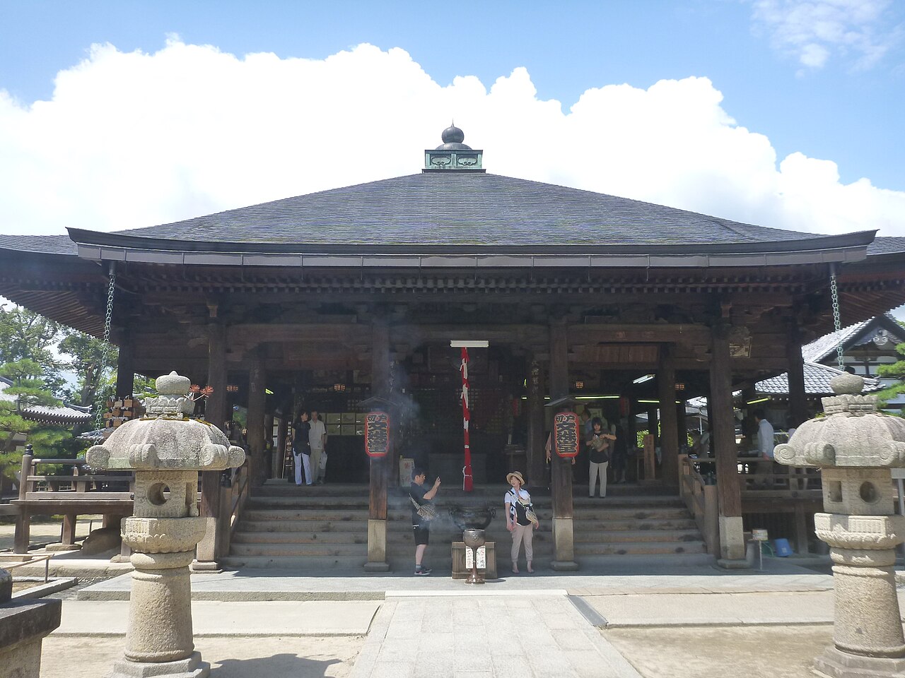 The Monju-do hall of Chion-ji temple in Miyazu with stone lanterns in front and visitors on the steps