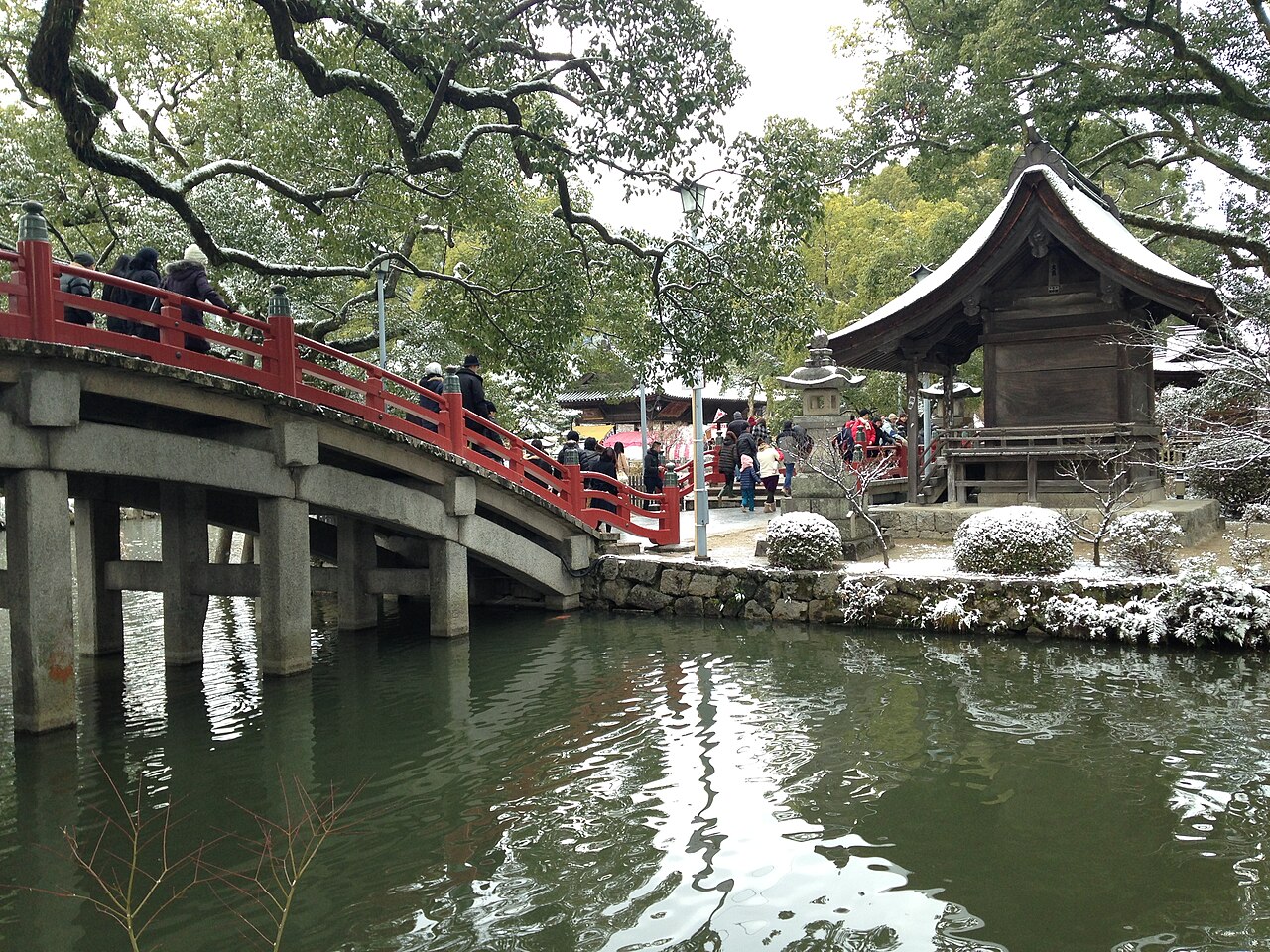The vermilion arched bridge over the heart-shaped pond at Dazaifu Tenmangu, with lingering snow.