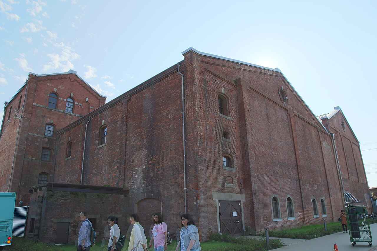 Visitors walking past the tall red brick walls of the Handa Red Brick Building