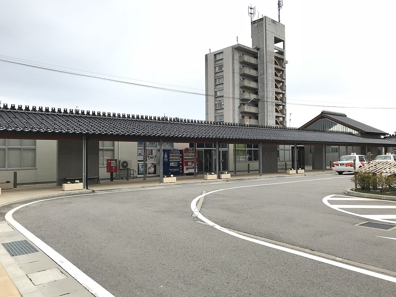 Low station building with a curving forecourt in front