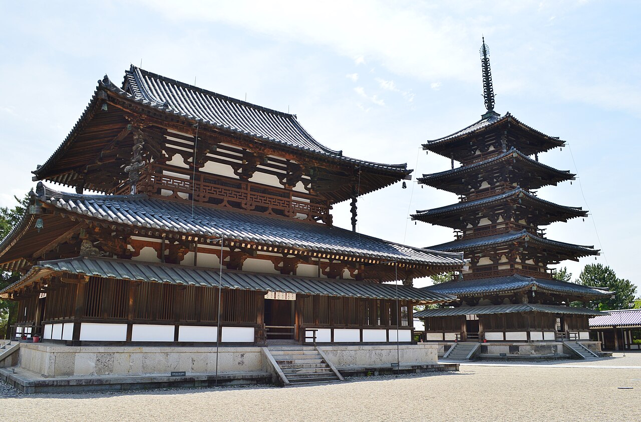 The two-storey Kondo main hall and the five-storey pagoda side by side on the gravel courtyard of Horyuji's western precinct, under a pale blue sky