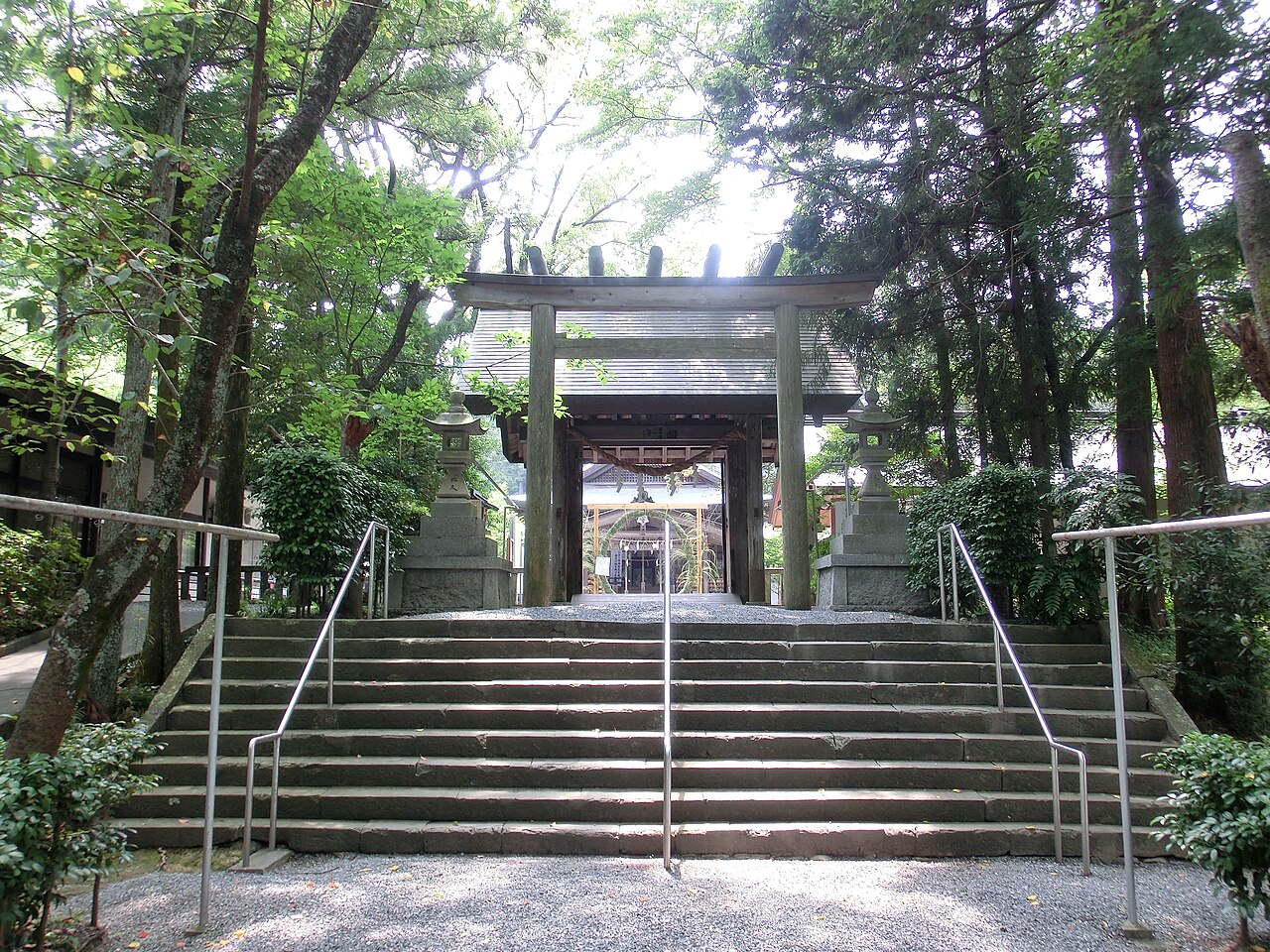 The stone steps and torii gate leading up to Iinoya Shrine among tall trees