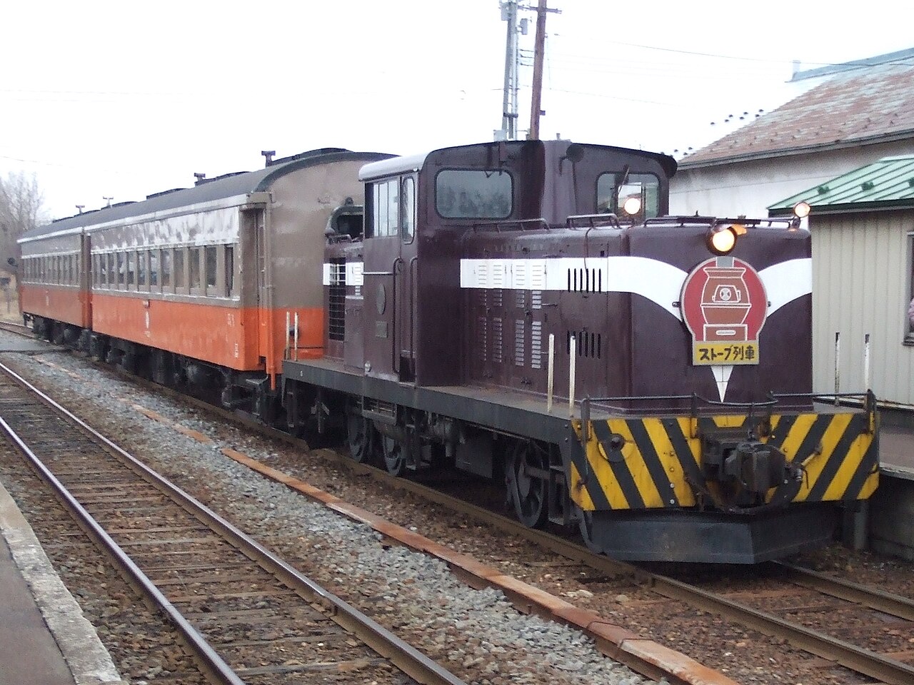 The dark-red locomotive of the Tsugaru Railway stove train standing at a platform