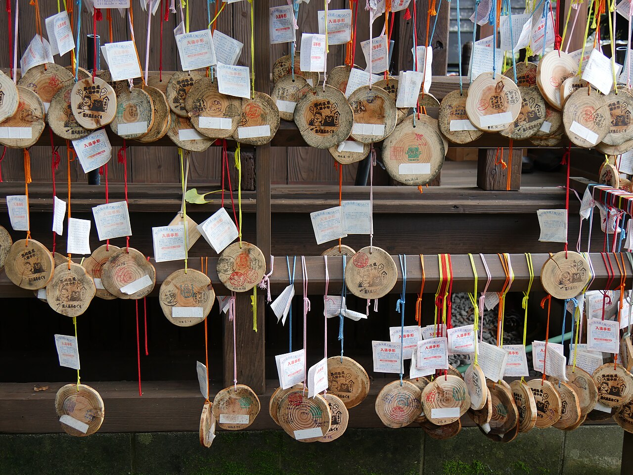 Rows of round wooden bath pass tokens hanging from a rack in Kurokawa Onsen
