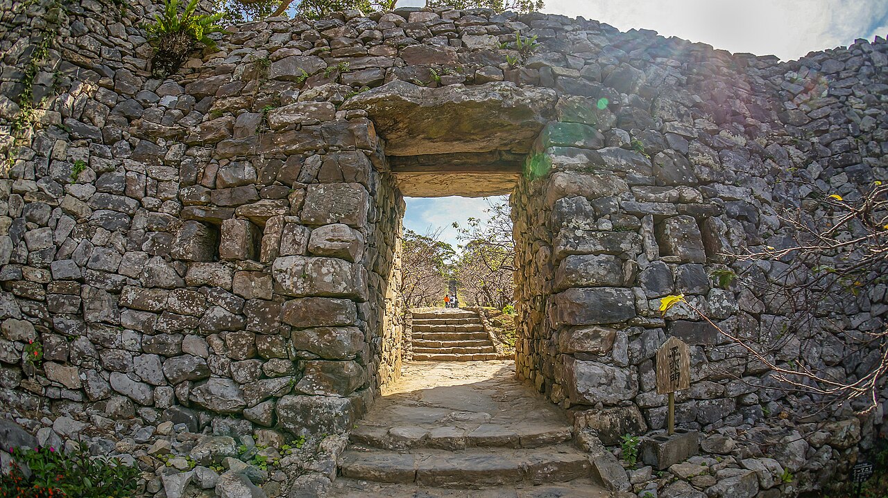 Stone steps lead through the Heiro Gate, a square opening in the thick limestone wall of Nakijin Castle
