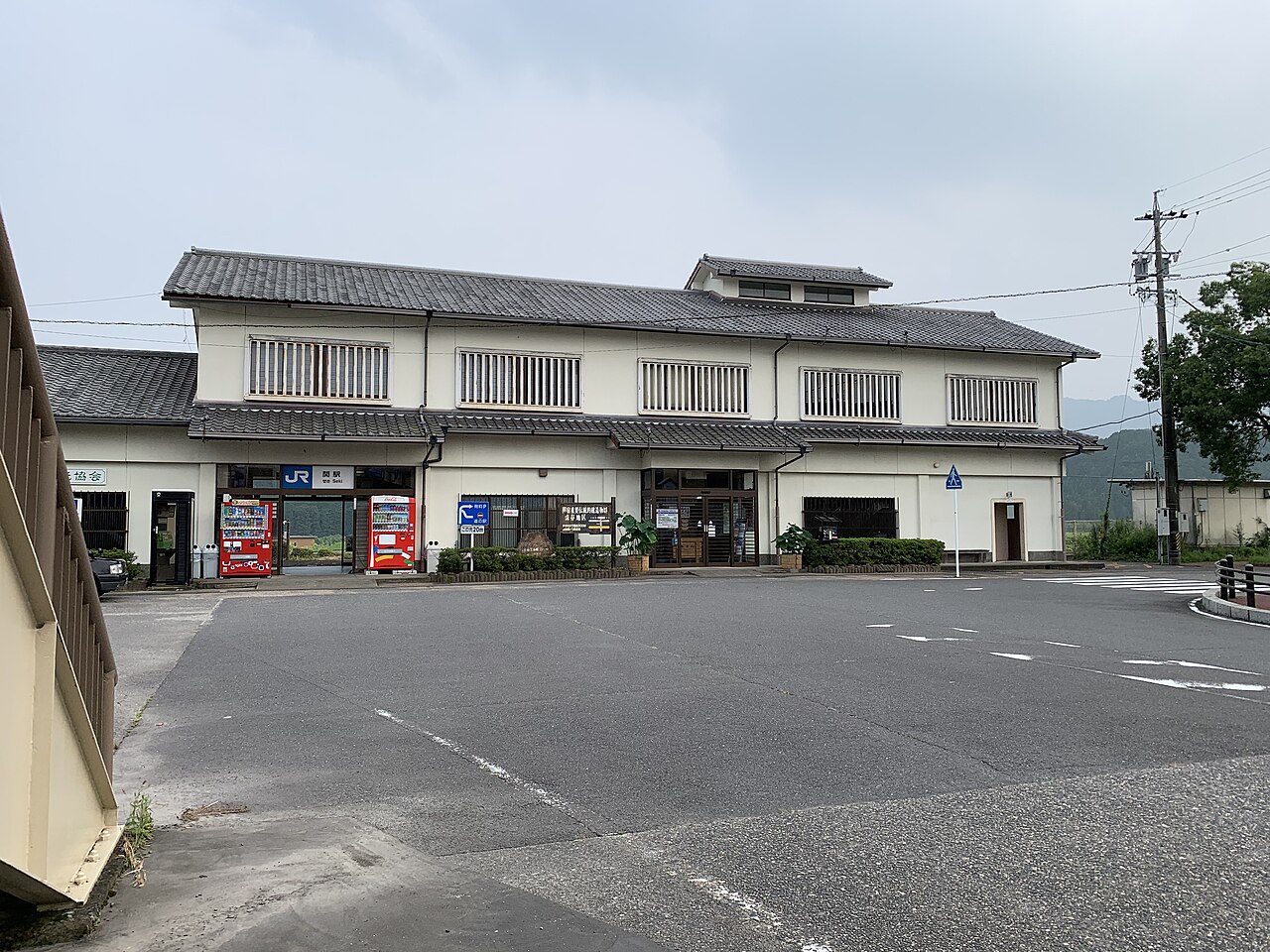 The two-storey JR Seki Station building with latticed windows and a tiled roof, seen across the station forecourt.