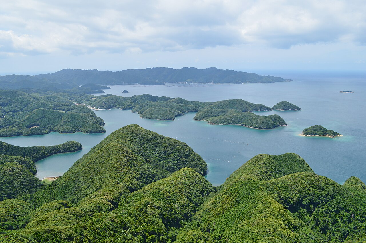 Green forested ridges and small islands scattered across the blue water of Asou Bay on Tsushima, seen from a high viewpoint