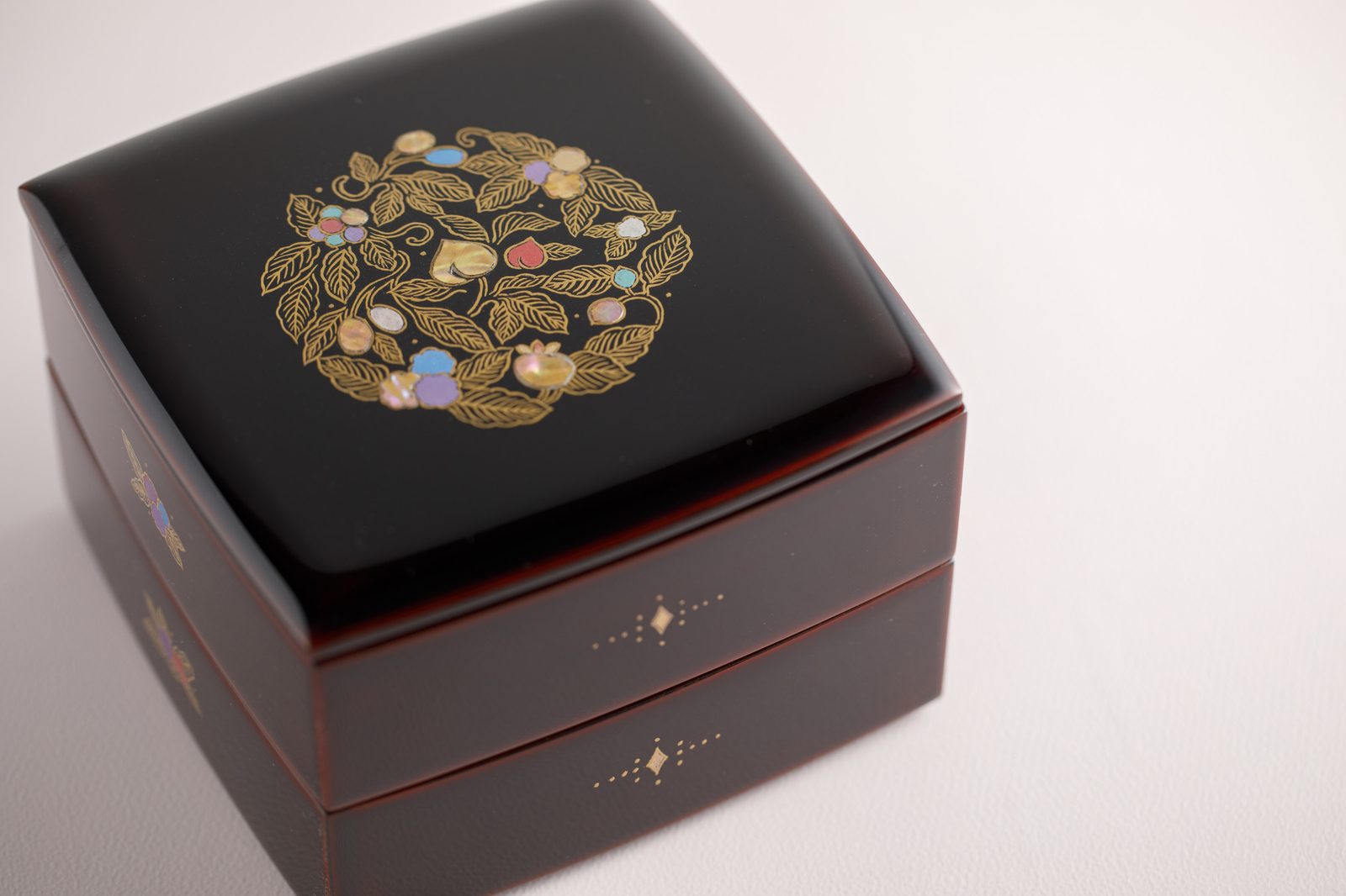 A two-tier Wajima-nuri lacquer box with a round gold and coloured maki-e design on the lid