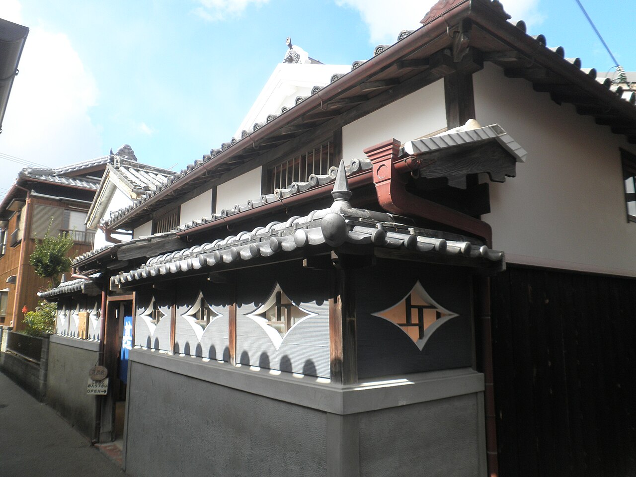 Tiled eaves and a grey-and-white wall with diamond-shaped panels on an old merchant building in Yuasa