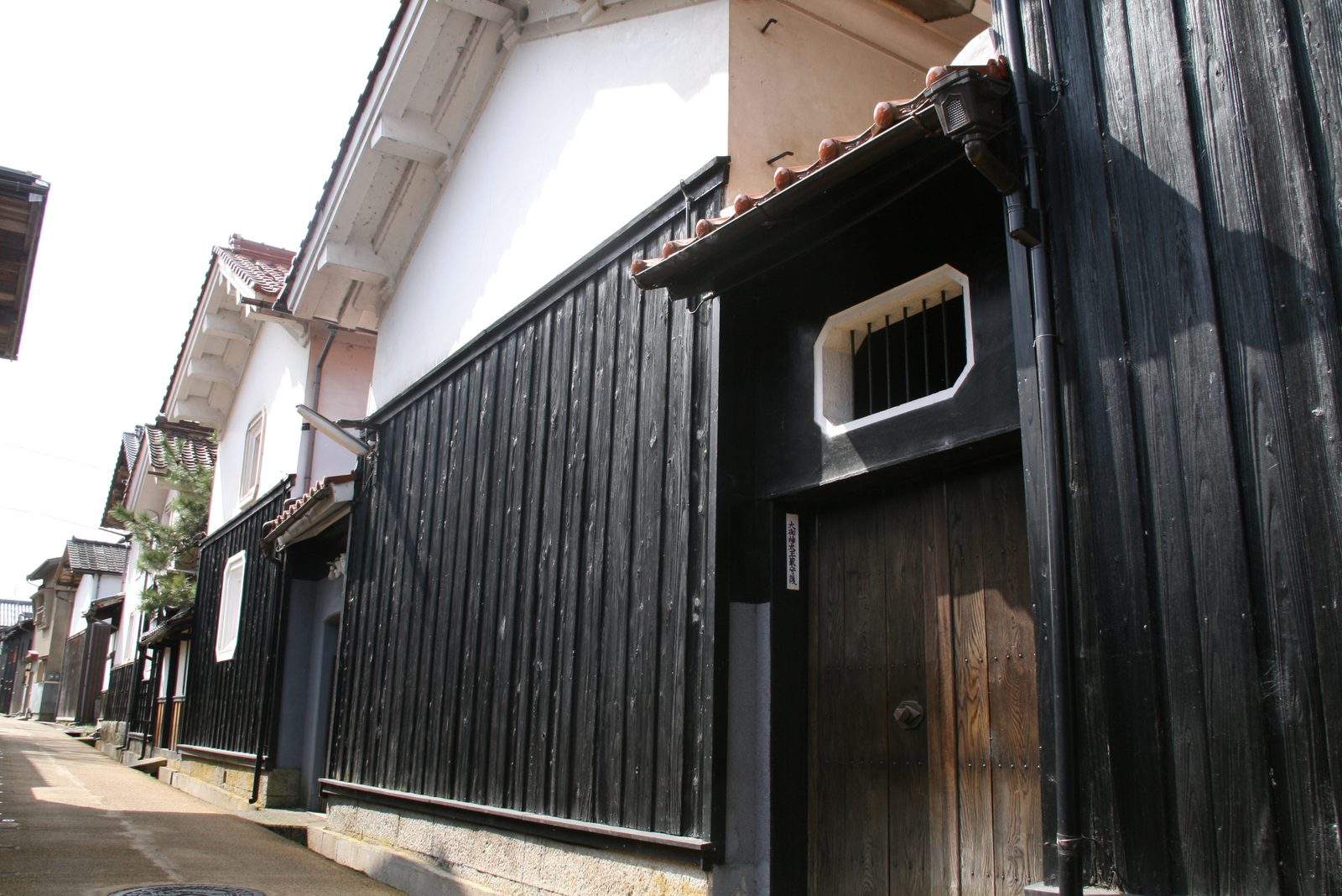 A narrow lane in Wakasa lined with black-timbered storehouses with white plaster walls and octagonal windows