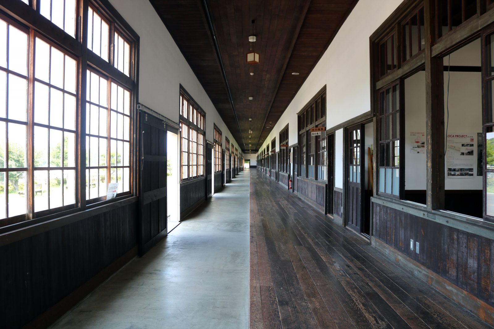 A long wooden school corridor with tall glazed windows on both sides, inside the former Uwa elementary school that is now the Uwa Rice Museum.