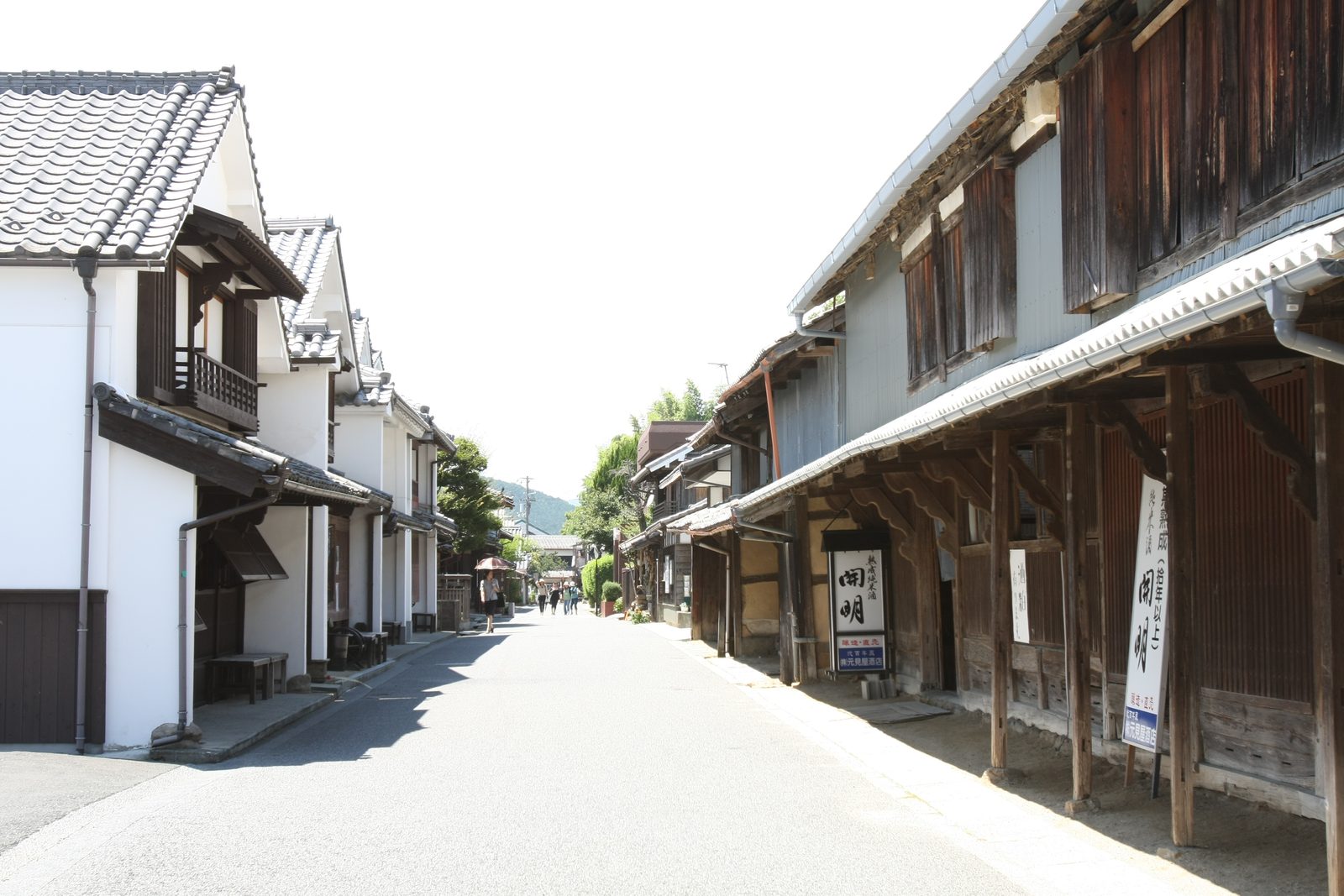 A quiet paved lane lined with white-plastered and weathered wooden townhouses with tiled eaves in Unomachi, Uwa, Seiyo, Ehime.