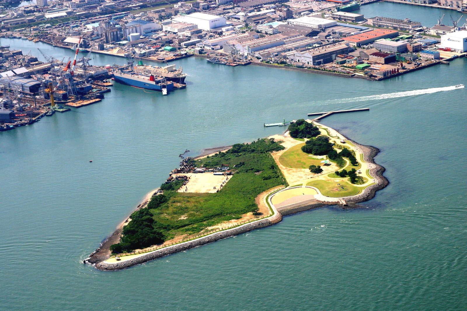 Aerial view of the low, flat island of Ganryujima in the Kanmon Strait, with the port behind it