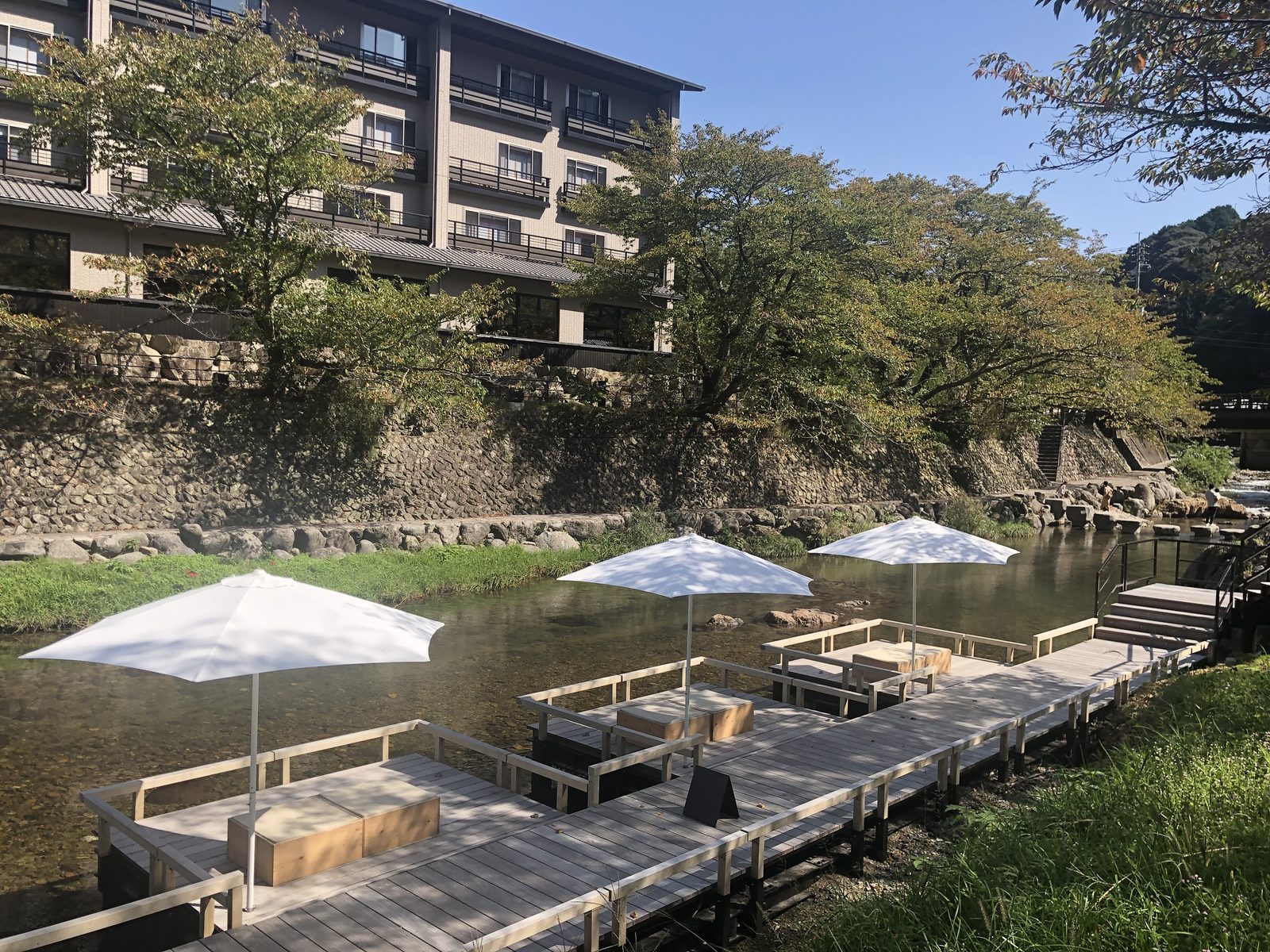 White parasols over wooden riverside platforms along the stream at Nagatoyumoto Onsen in Nagato